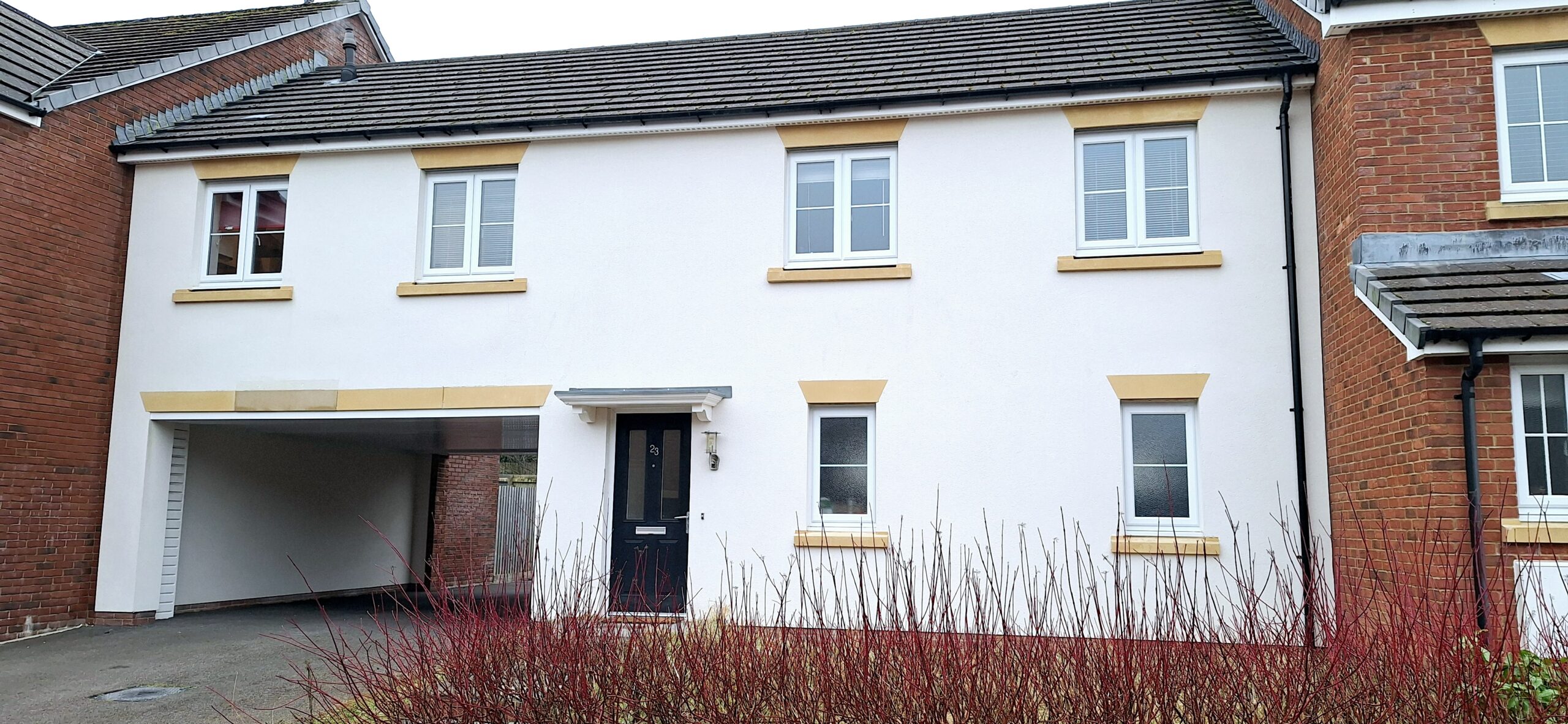 Flat with white exterior and archway leading to the car park.